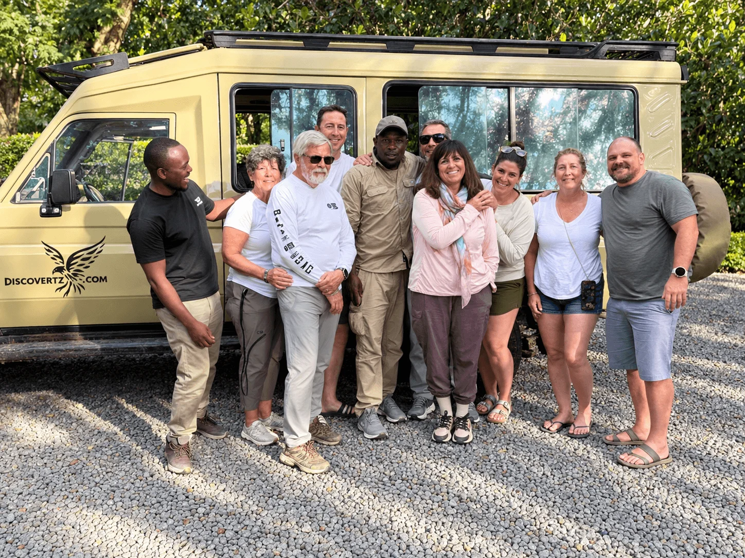 Safari travelers and guides standing together beside a DiscoverTZ vehicle