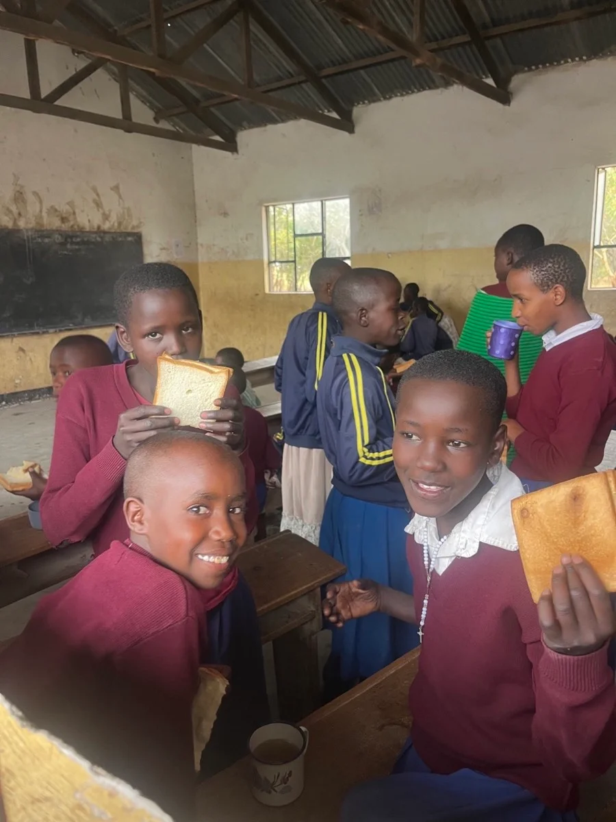 Tanzanian students sharing food together inside their classroom