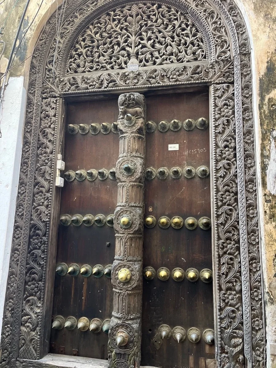 An intricately carved Stone Town wooden door with rows of brass studs
